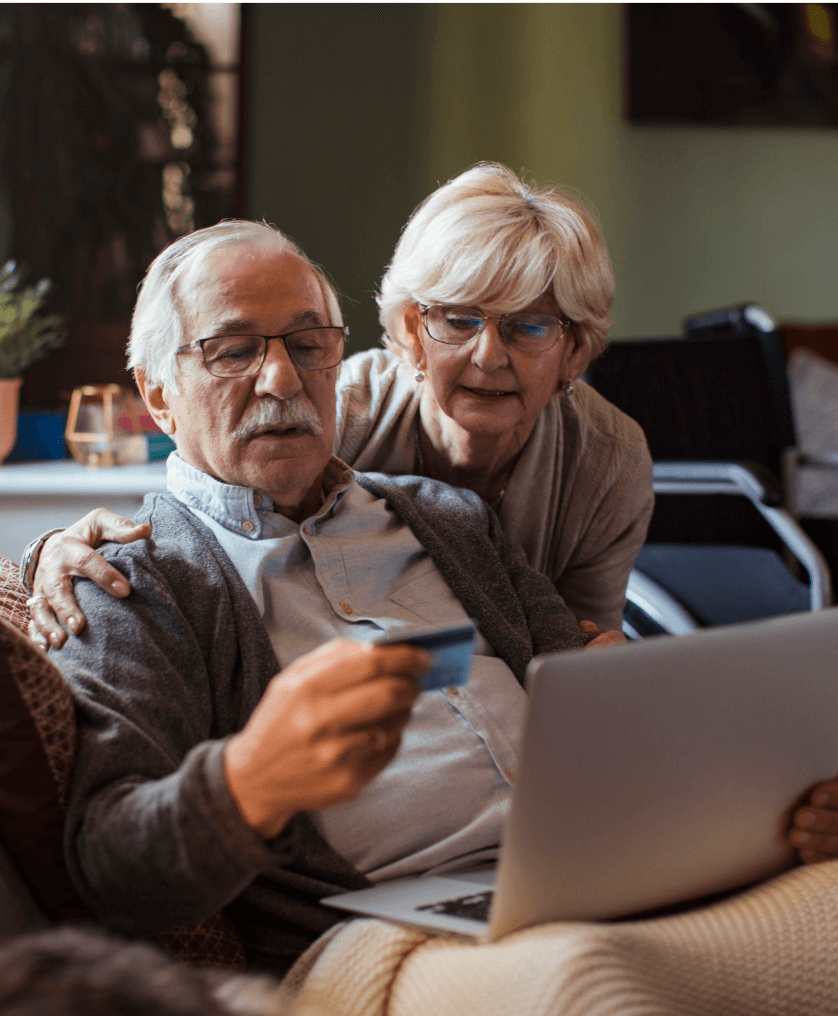 senior couple online shopping, with a laptop and charge card