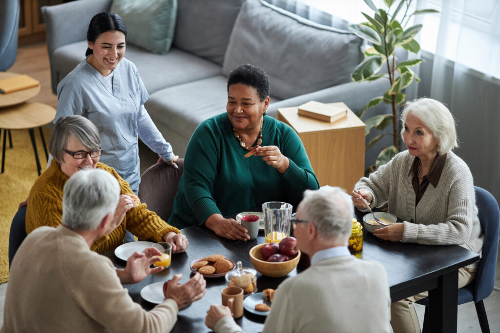 senior people sitting at table together and smiling eating breakfast