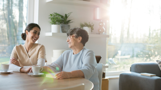 A caregiver sitting with a senior woman at a table