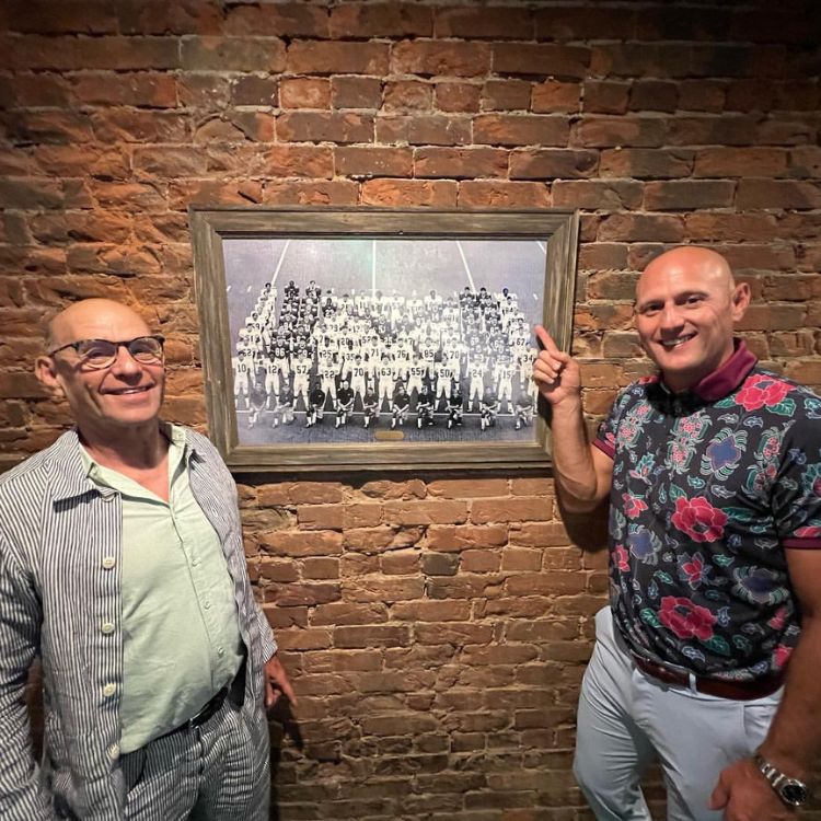 Bobby Petras points to a framed photograph of a football team.