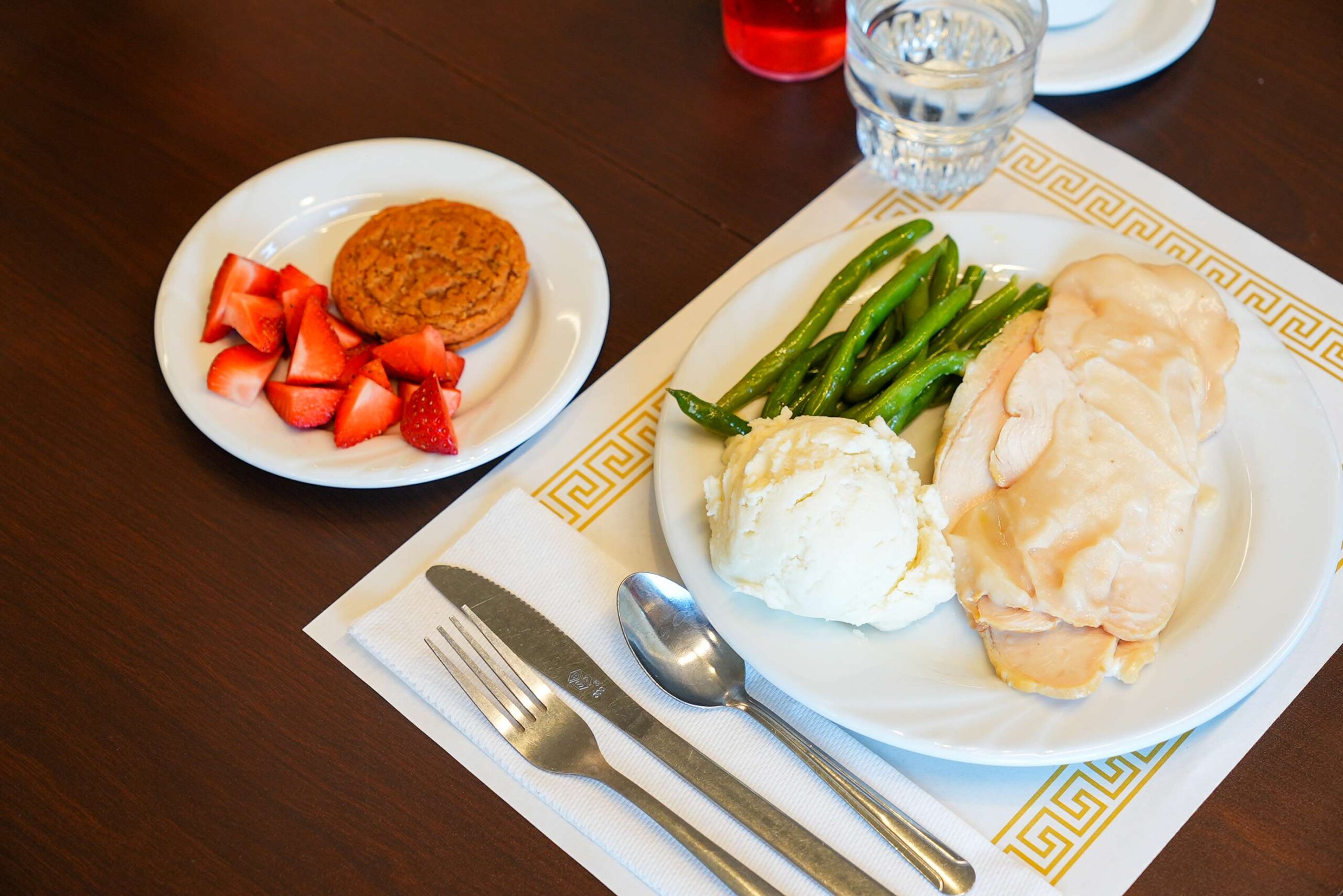 Turkey, mashed potatoes, and green beans, with fresh strawberries and and oatmeal cream cookie.