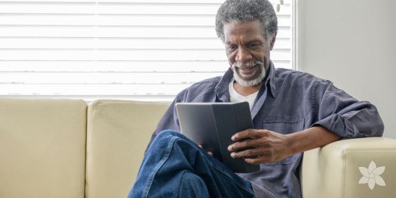 Senior man sitting on a couch looking at a tablet