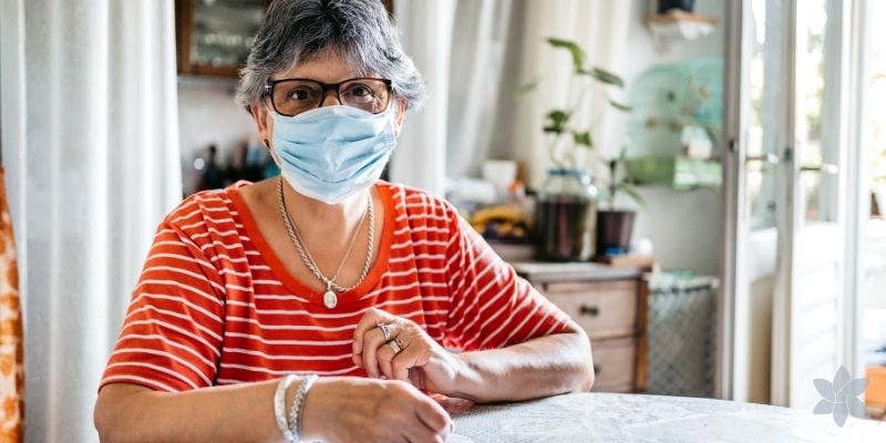 Senior woman wearing a medical mask sitting and looking at the camera