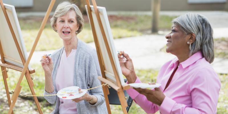 Two senior women outside painting