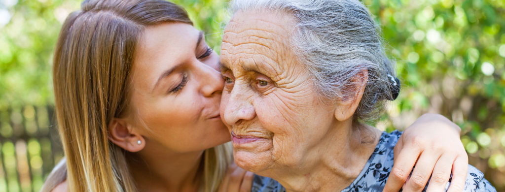 daughter kissing her senior mother's cheek